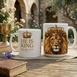 Puede incluir: Dos tazas de cerámica blanca con una ilustración detallada de un león con una corona dorada enjoyada. Una taza muestra el texto HE IS KING y Revelation 19:16 en letras doradas, mientras que la otra muestra el rostro del león.