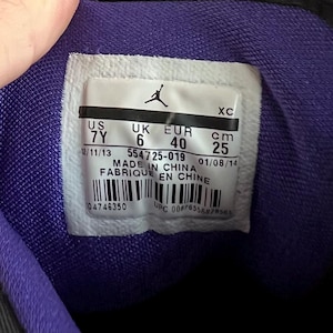 May include: Close-up of a shoe's size tag with the text "US 7Y, UK 6, EUR 40, cm 25", "12/11/13 554725-019 01/08/14", "MADE IN CHINA", "FABRIQUE EN CHINE", "04746350 UPC 00676556879563".