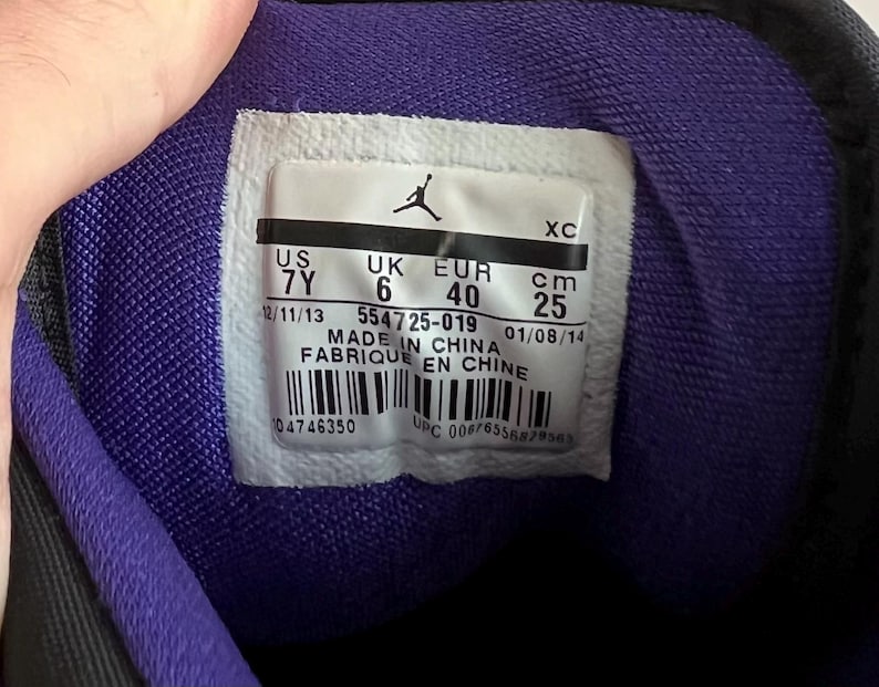 May include: Close-up of a shoe's size tag with the text "US 7Y, UK 6, EUR 40, cm 25", "12/11/13 554725-019 01/08/14", "MADE IN CHINA", "FABRIQUE EN CHINE", "04746350 UPC 00676556879563".