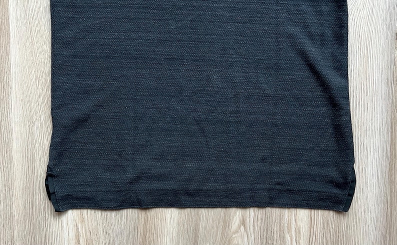 May include: A dark gray t-shirt with a textured, slightly rough surface.