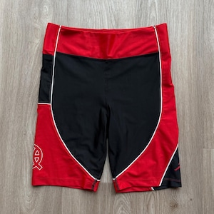 May include: Black and red athletic shorts with white trim. The shorts feature a high waistband and a logo on the left leg. Made from breathable, athletic fabric, these shorts are designed for comfort.