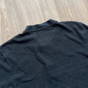 May include: A dark gray long-sleeved shirt made of a textured fabric.