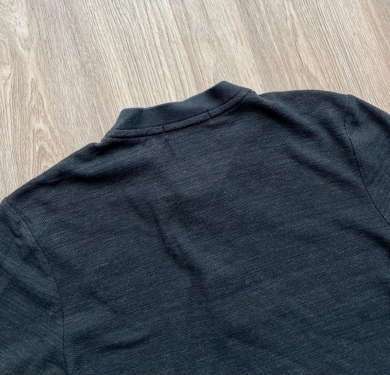 May include: A dark gray long-sleeved shirt made of a textured fabric.