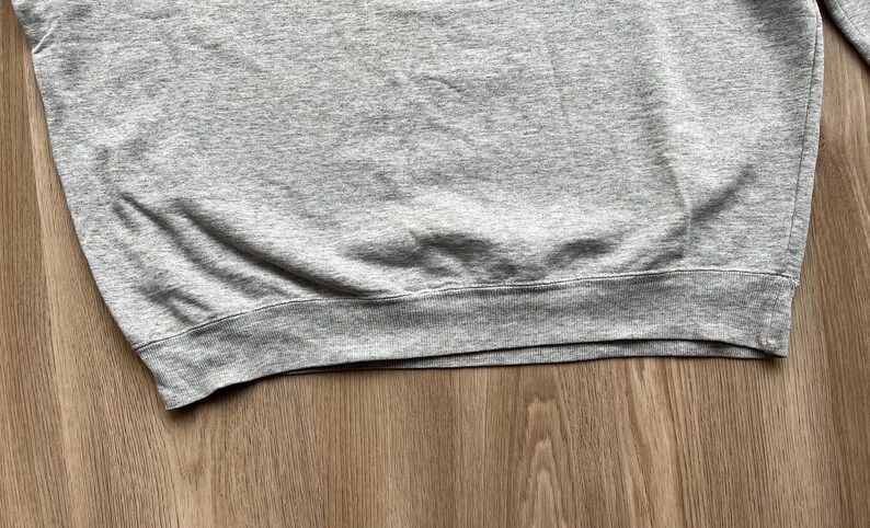 May include: A grey sweatshirt with a ribbed hem.