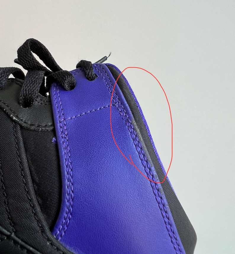 May include: Close-up of a black and purple sneaker with a visible seam along the side. The seam is slightly frayed.