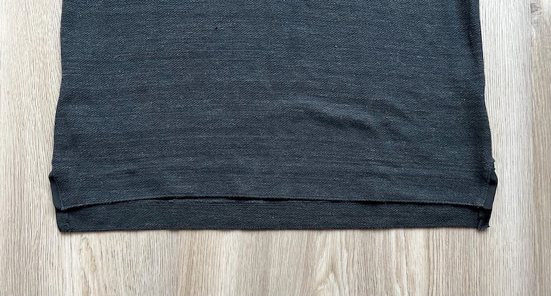 May include: A dark gray t-shirt with a ribbed texture and a hemmed bottom edge.