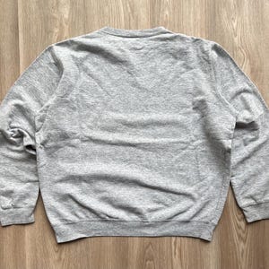 May include: A grey long-sleeved sweatshirt with a crew neck.