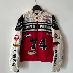 May include: A red, white, and black racing jacket with the number "74" on the front. The jacket has various sponsor logos, including "Speed Freak", "Exorzist", "NGK", "Hurric", "Castrol", and "Salto".