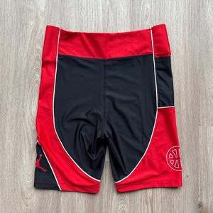 May include: Black and red athletic shorts with white trim. The shorts have a red waistband and side panels, with a black center. The Jordan logo is visible on the left leg, and a circular design on the right leg.