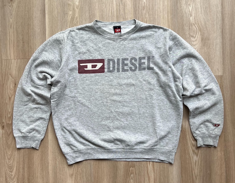 May include: Grey long-sleeved sweatshirt with a red and white Diesel logo.