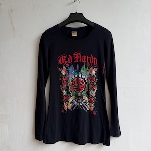 May include: A black long-sleeve t-shirt featuring a graphic print with the red text Ed Hardy. The design includes a central red rose, skulls, blue and green swallows, and a banner with the text Love Kills Slowly, all set against a dark background.