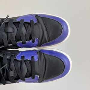 May include: A pair of black and purple high-top sneakers with black laces.