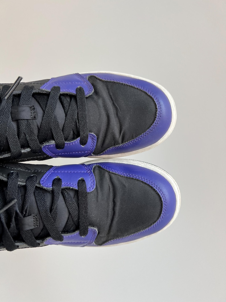 May include: A pair of black and purple high-top sneakers with black laces.