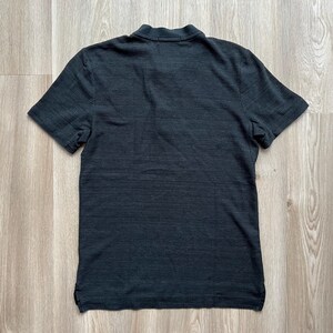 May include: A black short-sleeved t-shirt with a textured, slightly distressed look.
