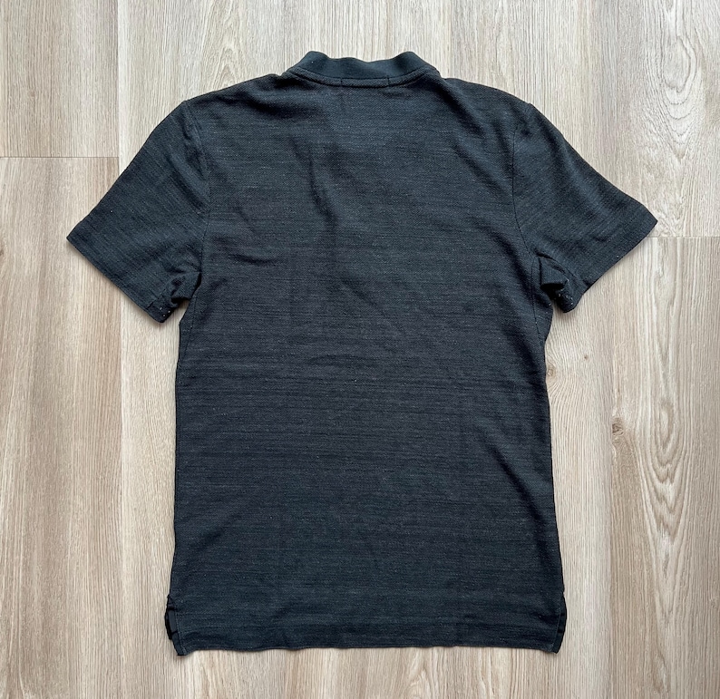 May include: A black short-sleeved t-shirt with a textured, slightly distressed look.