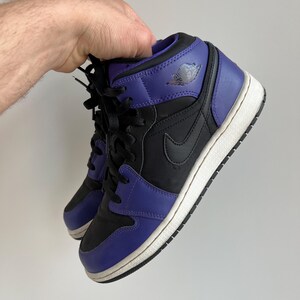 May include: Black and purple mid-top sneakers with a white sole and a Nike swoosh logo on the side.