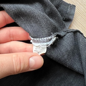 May include: A black Nike tag with white text and a white swoosh logo. The tag reads "M 891773-010 888411952879".