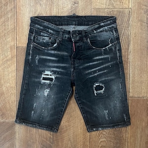 Może przedstawiać: Czarne szorty dżinsowe z przetarciami i czerwonym szwem na tylnych kieszeniach.