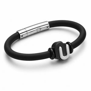 May include: Black silicone bracelet with a silver-tone clasp and a black accent piece featuring a silver-tone letter "U". The bracelet is a simple, modern design.