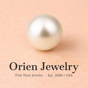 May include: A single, smooth, spherical white pearl with a soft luster. Below the pearl, the text reads: Orien Jewelry, Fine Pearl Jewelry &middot; Est. 2006 | USA. The pearl is centered above the black text, which is printed on a light peach-colored background.