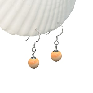 May include: A pair of silver dangle earrings with orange and white striped round beads.
