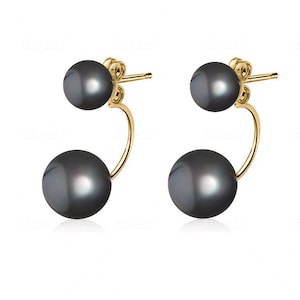 May include: A pair of gold earrings with two black pearls on each earring. The pearls are attached to a curved gold bar.