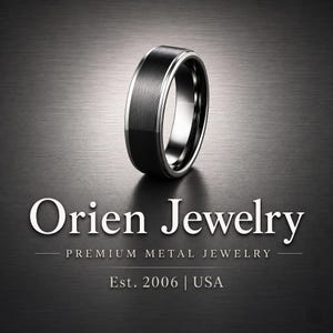 May include: A black ring with a brushed metal finish and a silver-colored inner band. The ring is displayed on a dark gray surface. The text "Orien Jewelry" is displayed in white, along with "Premium Metal Jewelry" and "Est. 2006 | USA".