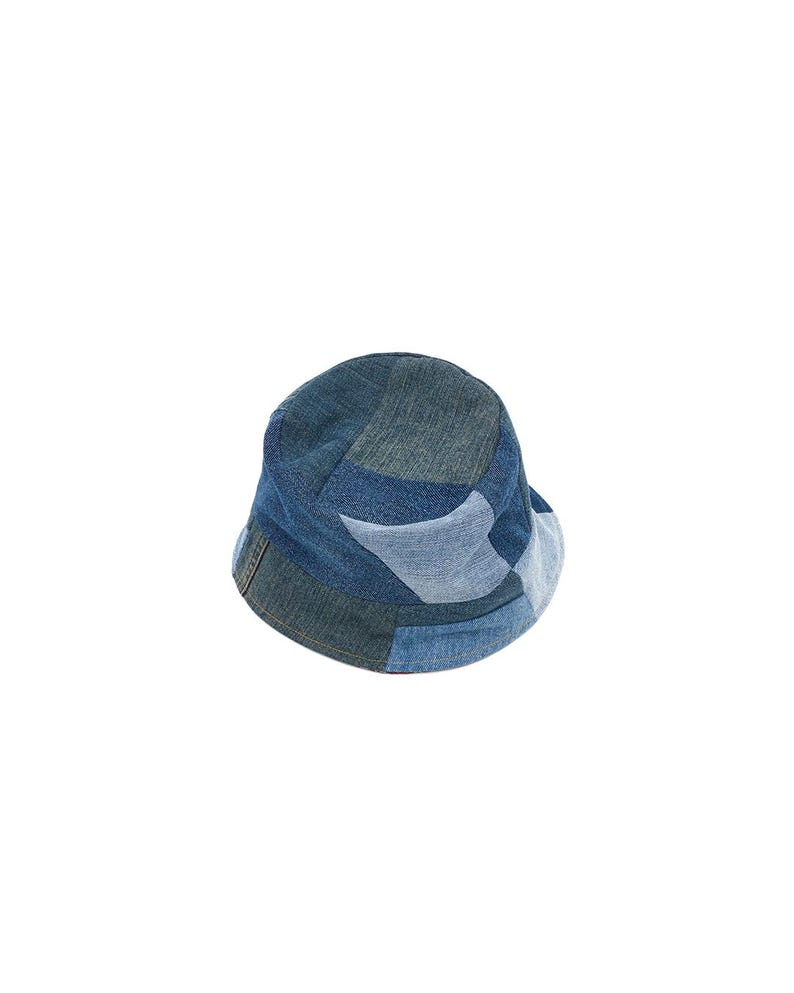 May include: A blue denim bucket hat with a patchwork design. The hat is made of different shades of blue denim and has a wide brim.