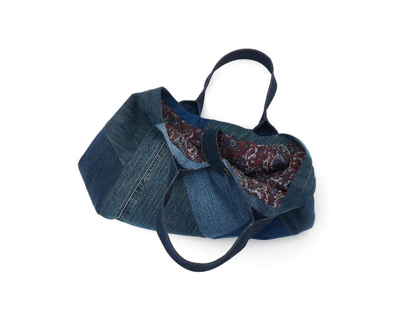 May include: A blue denim tote bag with a paisley patterned lining. The bag is made from recycled denim and has a patchwork design.