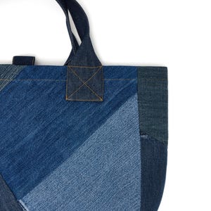 May include: A blue denim tote bag made from patchwork fabric. The bag has a single top handle and a rectangular shape.