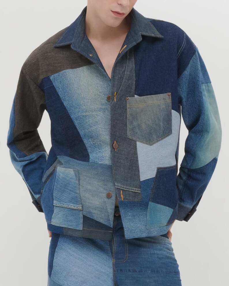 Puede incluir: Una chaqueta vaquera azul con un dise&ntilde;o de patchwork. La chaqueta tiene cuello, mangas largas y cierre de botones. La chaqueta est&aacute; hecha de diferentes tonos de mezclilla azul y tiene un bolsillo en el pecho izquierdo.