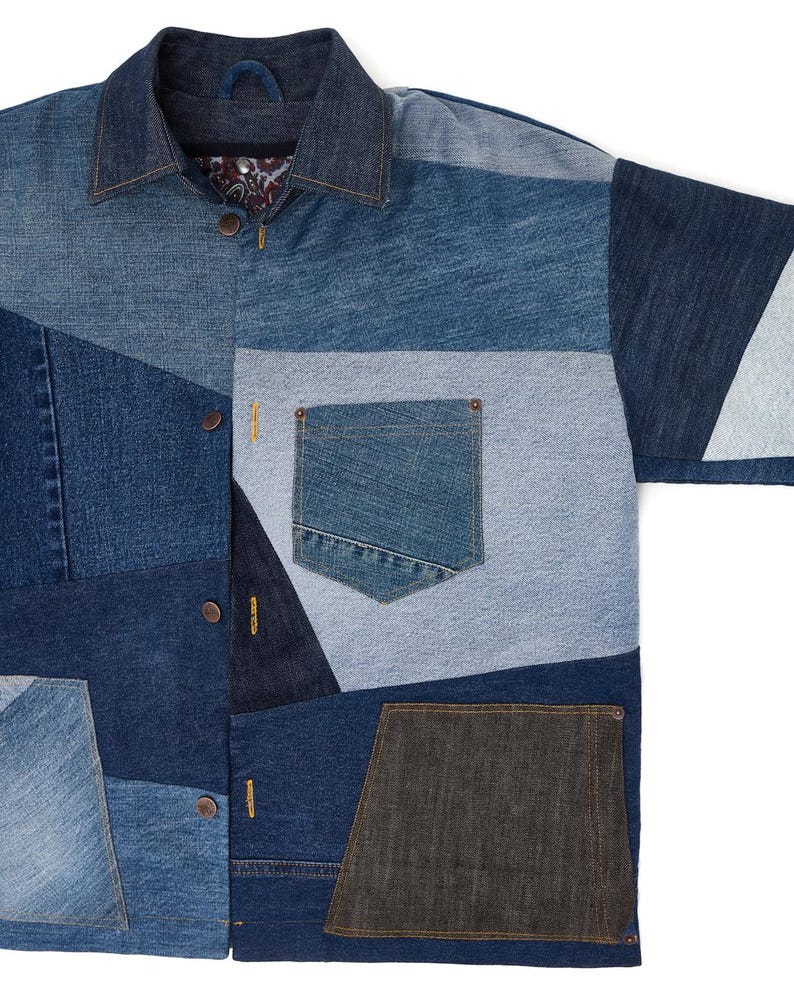 Puede incluir: Una camisa vaquera azul hecha de diferentes tonos de tejido vaquero. La camisa tiene un cierre de botones en la parte delantera, un cuello y un bolsillo de parche en el pecho izquierdo. La camisa est&aacute; hecha de un mosaico de diferentes tejidos vaqueros.