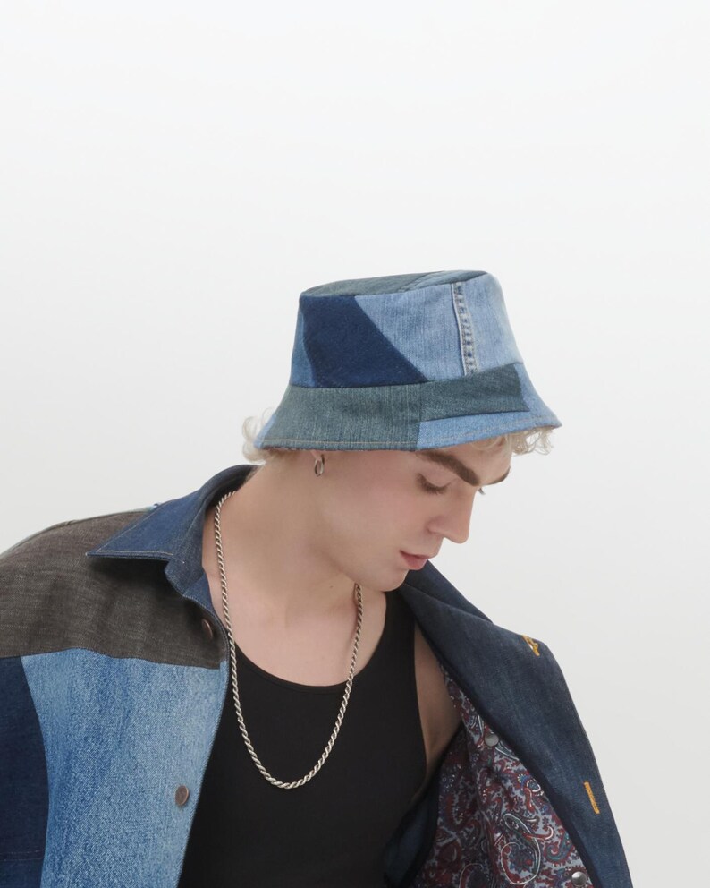 May include: A blue denim bucket hat made from patchwork fabric. The hat has a wide brim and a flat crown.