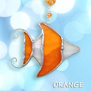 May include: Orange stained glass fish suncatcher with silver accents hanging from a silver chain with orange and clear beads. The fish has a white stripe down the middle of its body. The word "ORANGE" is printed below the fish.