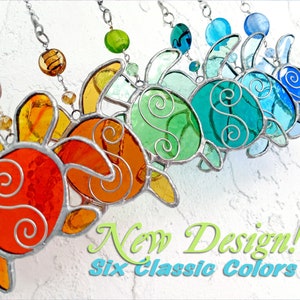 May include: Six stained glass turtle ornaments hanging from silver chains. The turtles are in a rainbow of colors, from orange to blue. The text "New Design! Six Classic Colors" is at the bottom of the image.