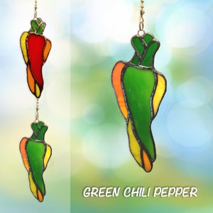 May include: A stained glass green chili pepper hanging ornament with yellow and orange accents. The ornament is suspended from a gold chain.