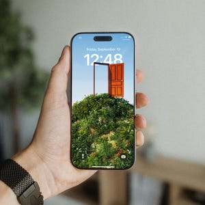 May include: A smartphone displaying a digital art image of a wooden door set in a green, grassy hill under a blue sky. The time is 12:48 on Friday, September 19. The phone is held in a hand with a black watch.