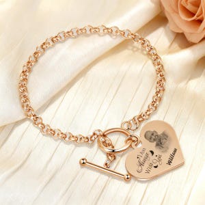 May include: Rose gold bracelet with a heart-shaped charm. The charm features a photo and the inscription "I am Always With You" and the name "William". The bracelet has a toggle clasp.