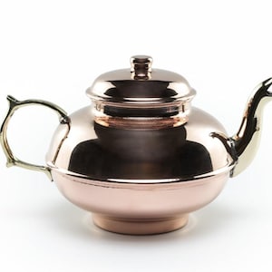 May include: A copper teapot with a brass spout and handle. The teapot has a rounded body and a domed lid.