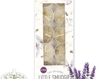 Op de afbeelding: Een doos met 12 "Little Smudgies" theelichtkaarsen met de geur "White Sage & Lavender". De doos toont "SOUL STICKS" en "4 Hrs Burn Time". Een takje lavendel ligt naast de doos. De kaarsen zitten in metalen houders.