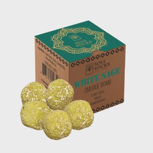 May include: A box of Soul Sticks White Sage Smudge Bombs. The box is brown with a teal green top and features the text "Soul Sticks" and "White Sage Smudge Bomb". Five green, round smudge bombs are in front of the box.