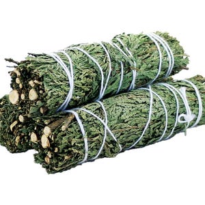 May include: Three bundles of dried green sage, tightly wrapped with white twine. The sage bundles are stacked together, showcasing the natural texture and color of the dried leaves and stems. The background is plain white.
