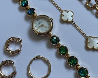 Gold watch with holographic green and blue gemstones