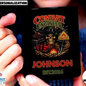 May include: Black mug featuring a skull in a military helmet with the words "COMBAT ENGINEER" and "DEMOLITION." The name "JOHNSON" and the year "EST.2026" are also displayed. The mug is held by a person.