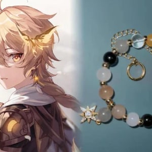 Peut inclure: Un bracelet doré orné de perles multicolores, dont des blanches, noires, jaunes et transparentes. Le bracelet est doté d'une chaîne et d'un charm. L'image comprend également un personnage de style anime aux cheveux blonds et aux détails dorés.