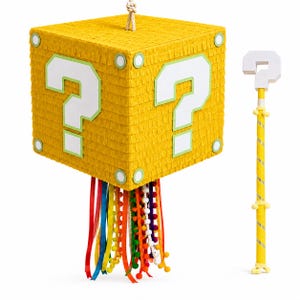 May include: A yellow cube-shaped pinata featuring white question marks on its sides, accented with green circular corner details. A cluster of colorful ribbons and pom-pom strands hangs from the bottom. A matching yellow stick with a white question mark topper is included.