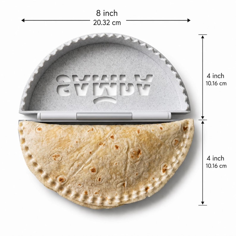 K&ouml;nnte beinhalten: Eine halbkreisf&ouml;rmige Empanada-Presse aus grau gesprenkeltem Kunststoff mit dem eingepr&auml;gten Wort SAMLA. Die Presse ist 20,32 cm breit und 10,16 cm hoch. Eine gefaltete Tortilla mit gewelltem Rand liegt in der unteren H&auml;lfte der Presse.