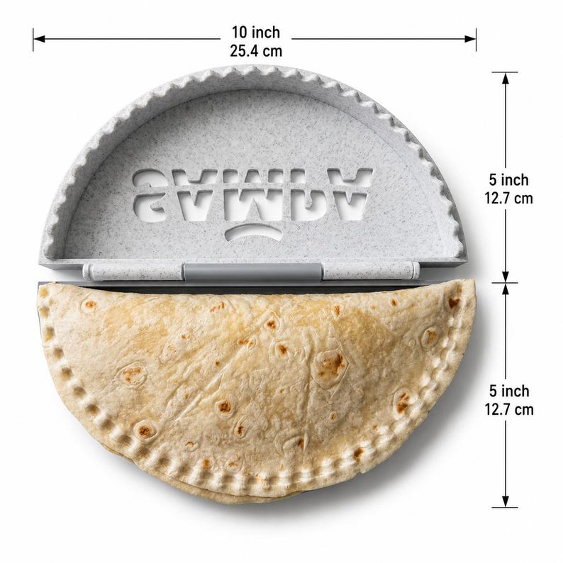 K&ouml;nnte beinhalten: Eine hellgrau gesprenkelte Kunststoff-Empanada-Presse mit einer Breite von 25,4 cm und einer Gesamth&ouml;he von 25,4 cm, in die das Wort SAMBA eingestanzt ist. Eine goldbraune, gefaltete Tortilla liegt in der unteren H&auml;lfte mit gewelltem Rand.