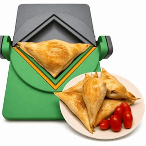 May include: A green and black kitchen appliance with a triangular press mechanism containing a golden-brown pastry. A white plate sits nearby, holding several similar triangular pastries and a small cluster of bright red cherry tomatoes.