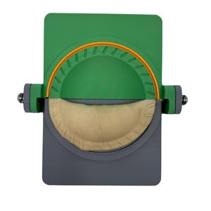 May include: A green and gray handheld pastry press with a beige pastry inside. The press has a circular opening with an orange rim.